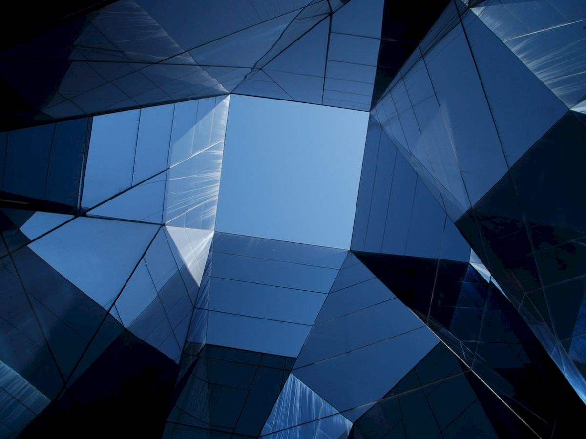 This image shows a geometric arrangement of reflective glass panels, creating a kaleidoscopic view of the sky.