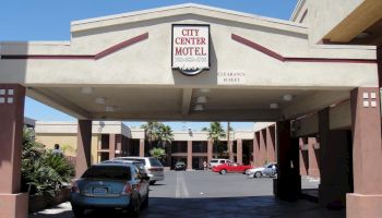 The image shows the entrance of City Center Motel with a few parked cars under the canopy. The signboard displays the motel's name and vacancy status.