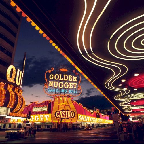 This image shows a vibrant street scene with neon signs for the Golden Nugget Casino and other establishments, likely in Las Vegas.