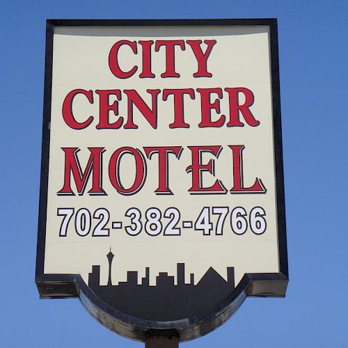 A sign reads "City Center Motel" along with the phone number "702-382-4766" against a clear blue sky, ending the sentence.