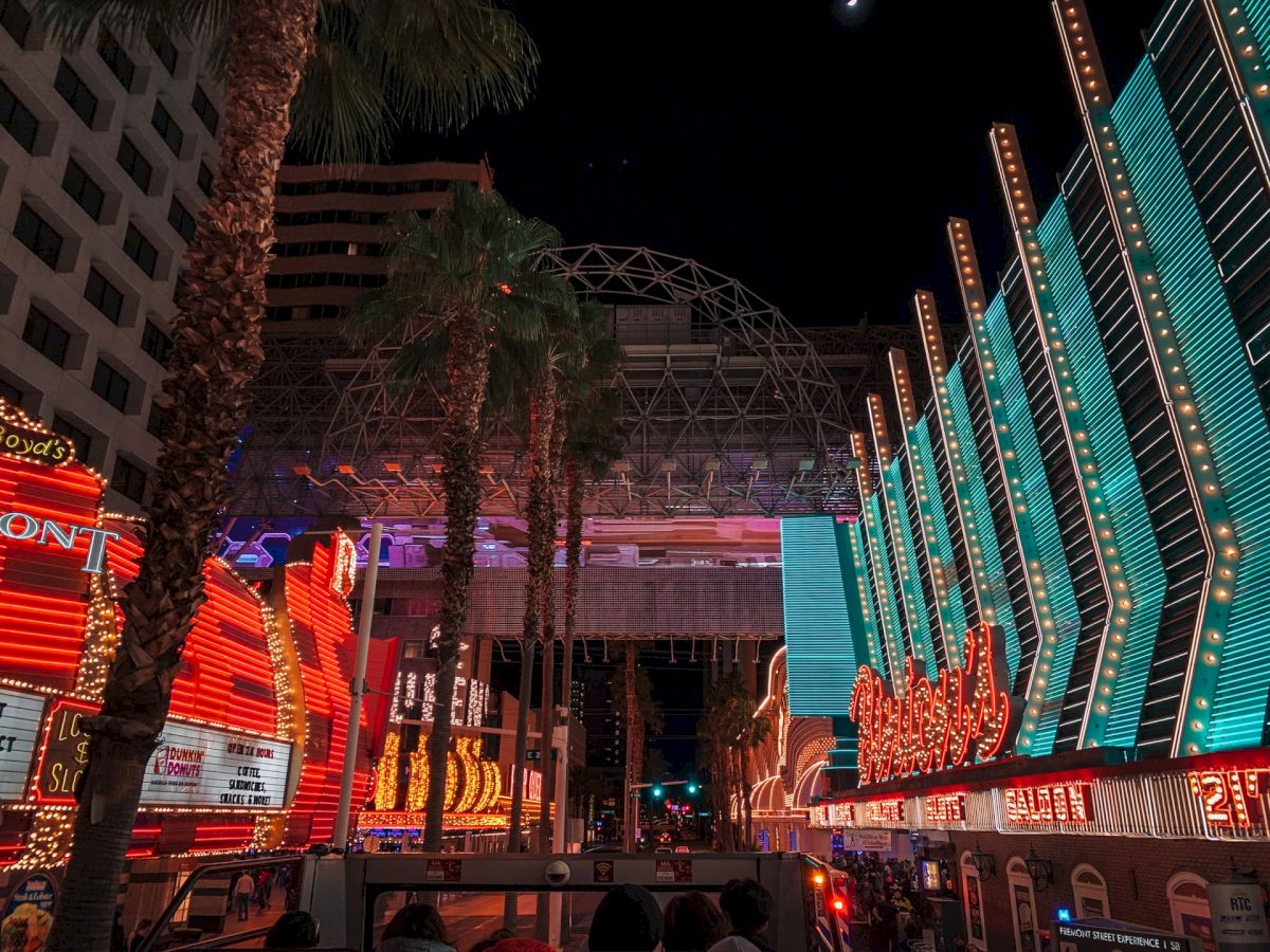 The image depicts a vibrant, illuminated street scene with colorful neon lights and signs at night, likely in a busy entertainment district .