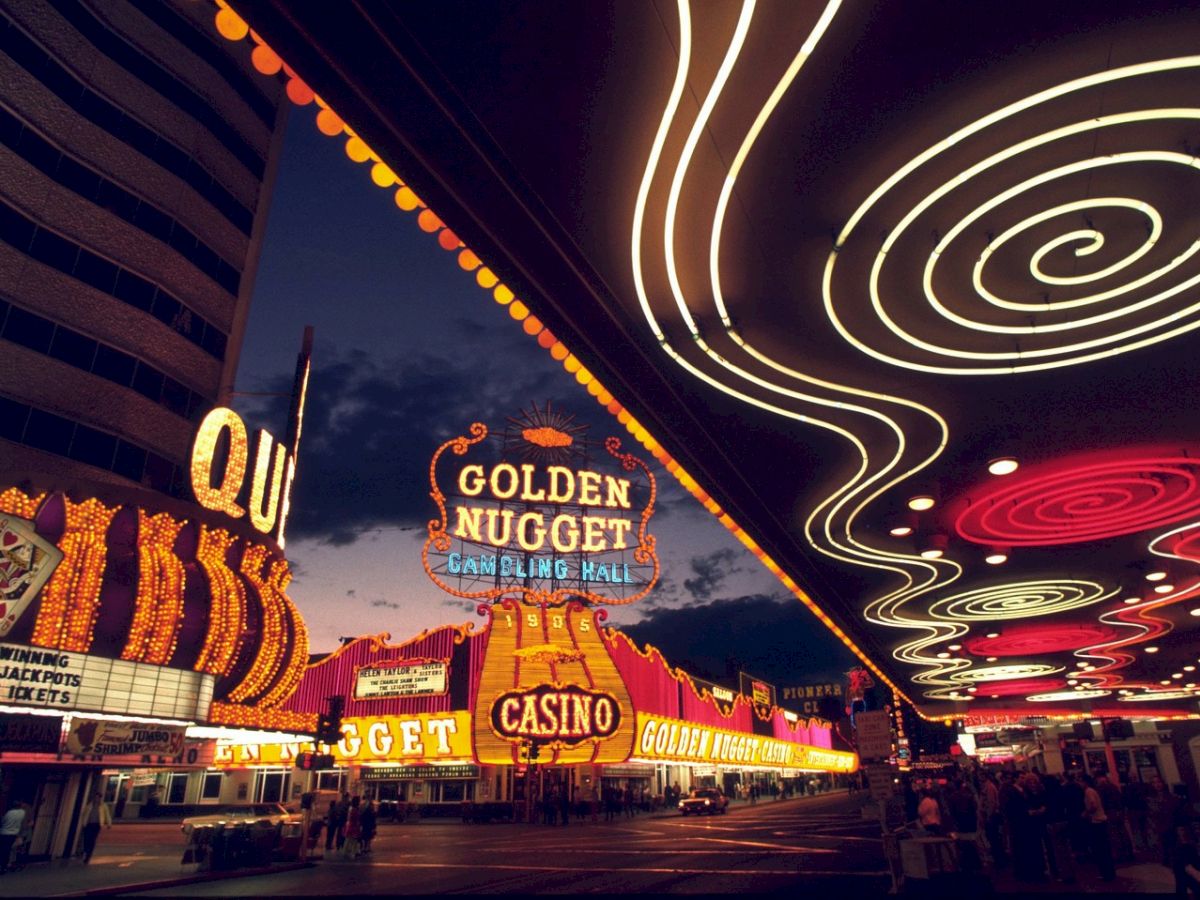 The image shows a brightly lit casino area, with neon signs, including the prominent 